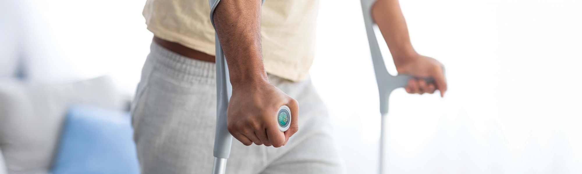cropped view of young black guy using crutches having leg injury or broken bone at home