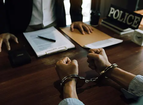 man at police desk in handcuffs