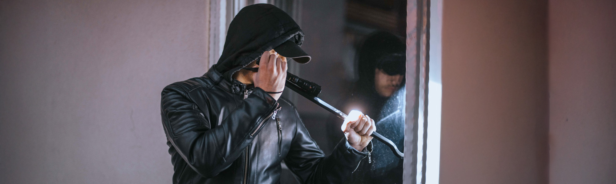 man using crow bar to break into house
