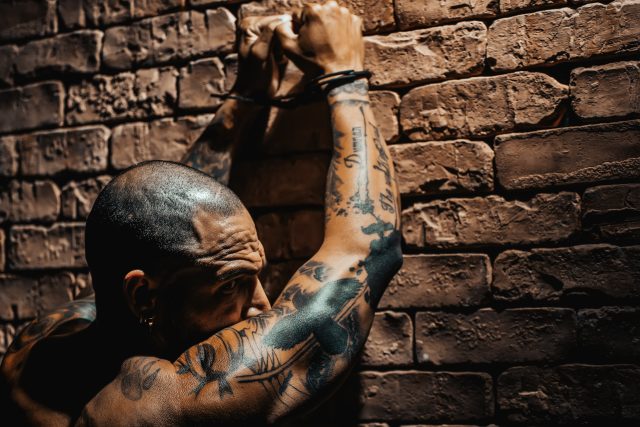 Person in handcuffs facing a brick wall during an arrest for a Georgia gang charge